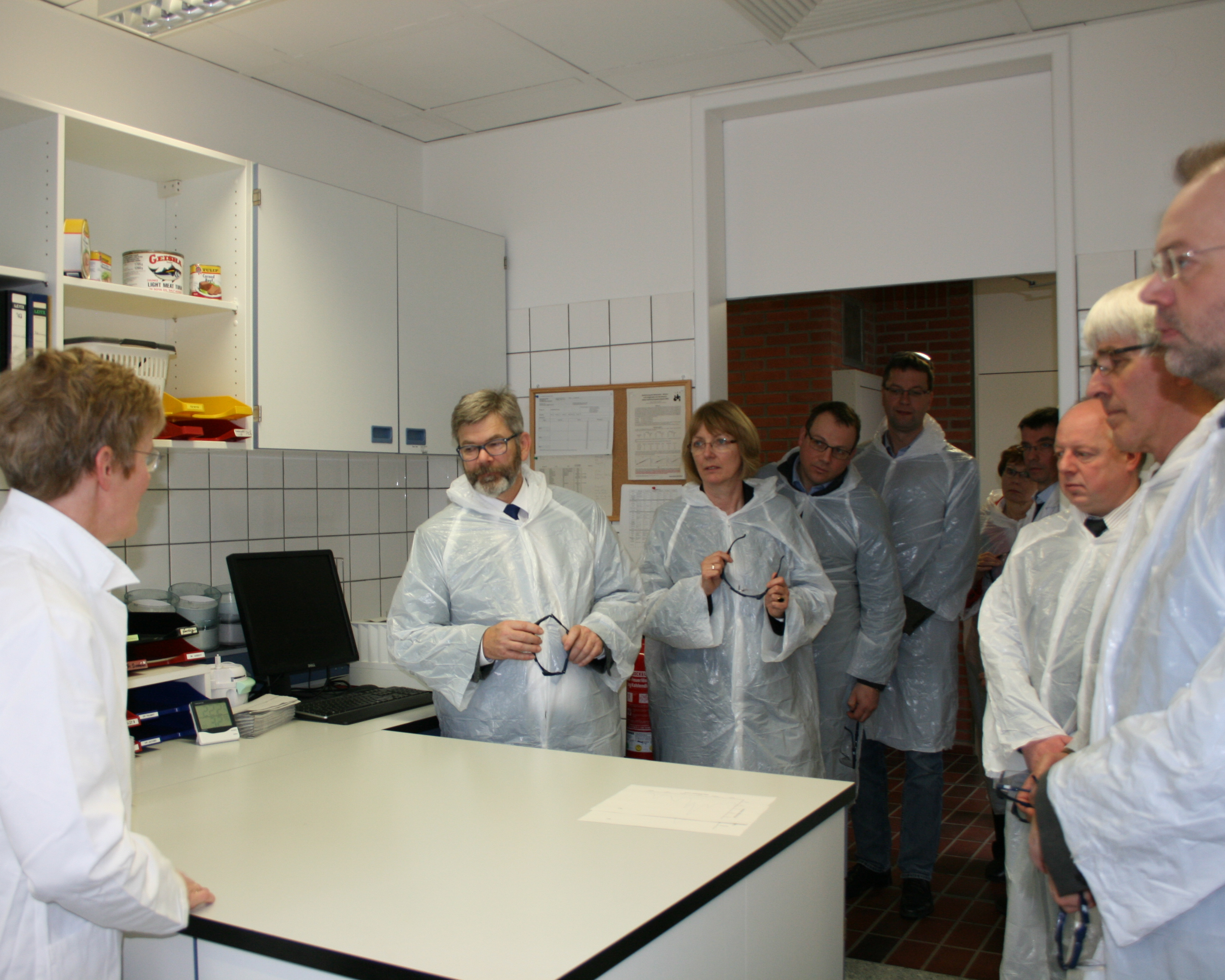Menschen in weißen Kitteln stehen um Tisch herum