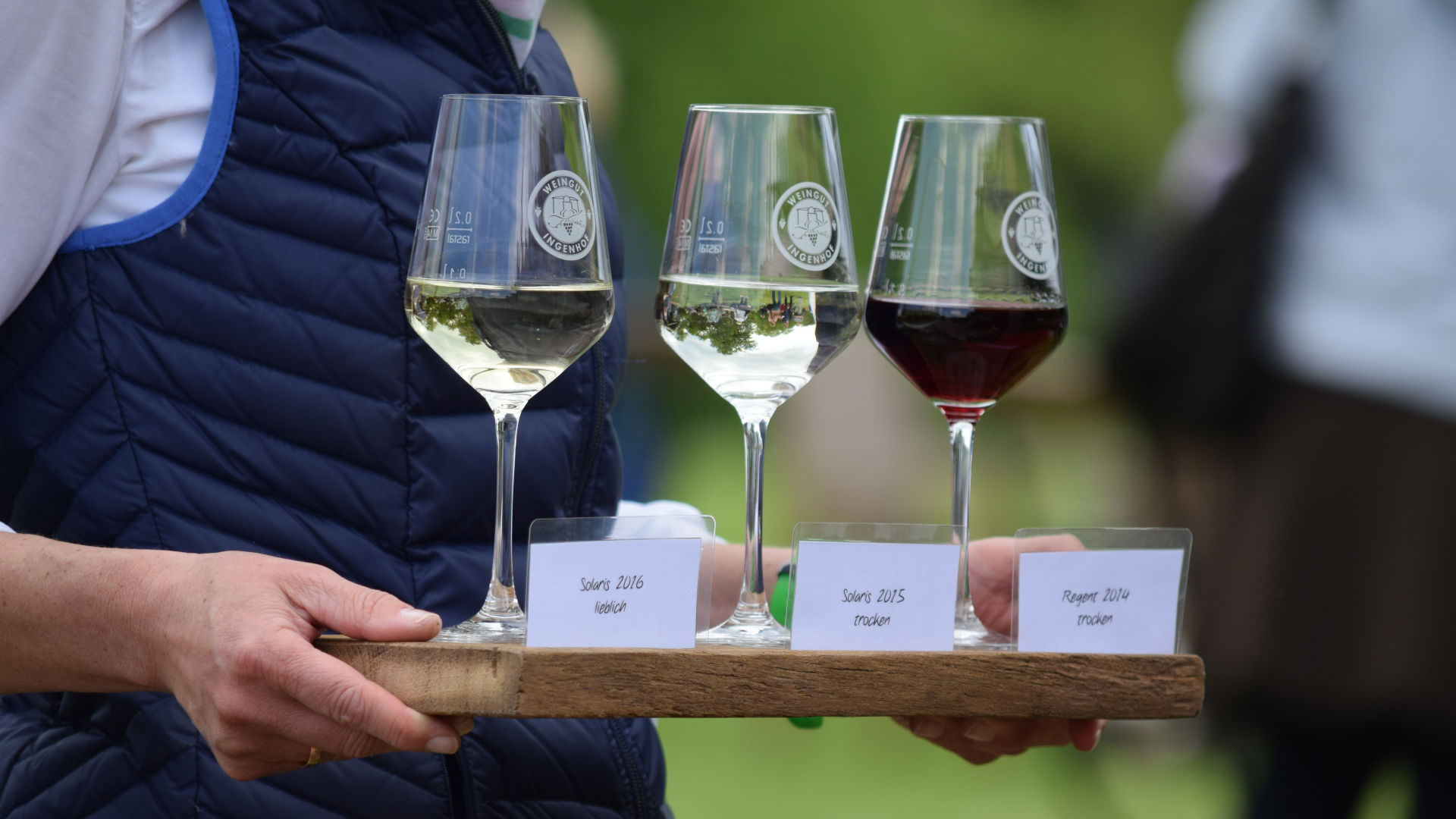 drei Gläser Wein werden auch einem Holztablett getragen