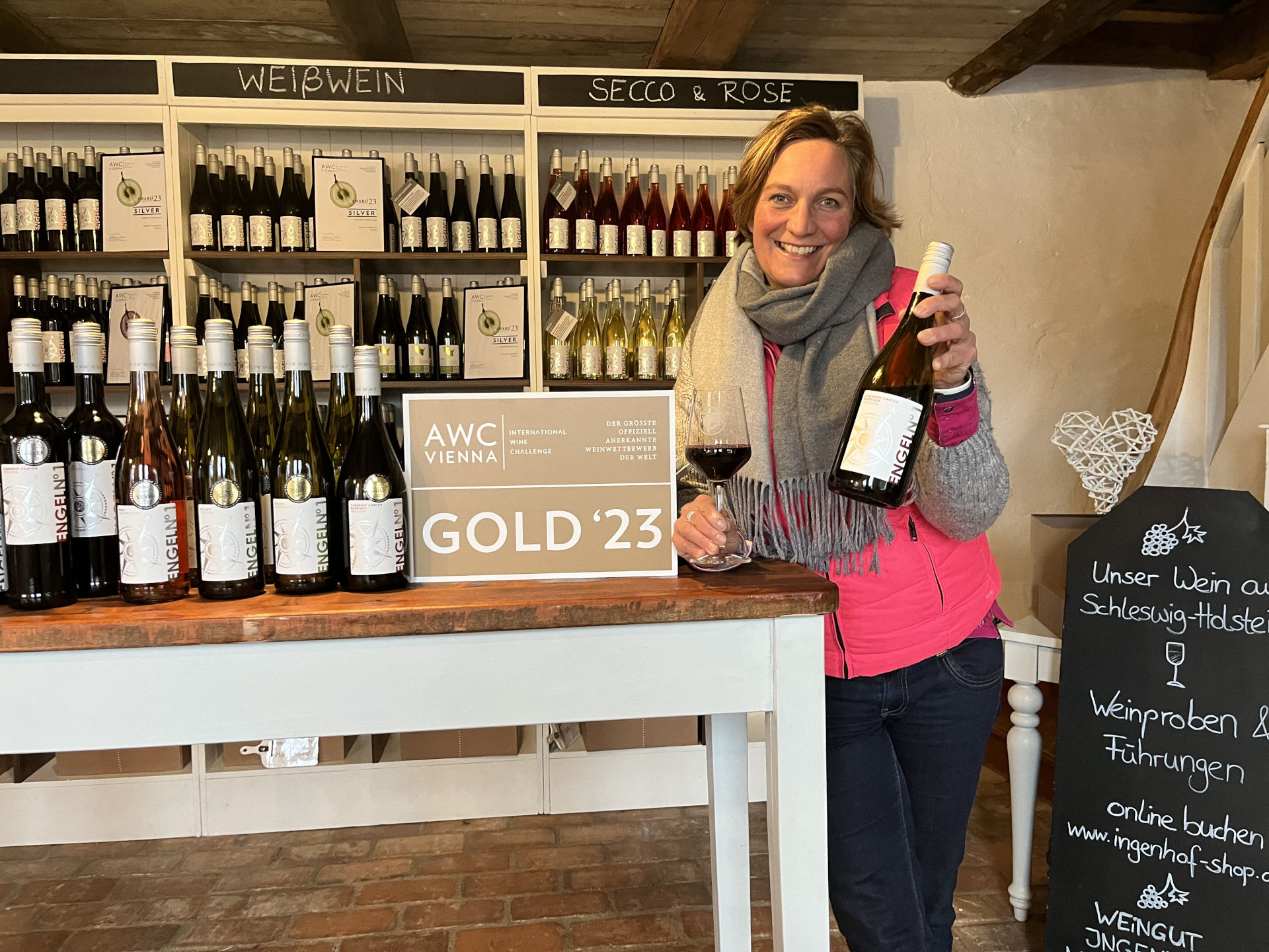 eine Frau steht am Weinverkaufstresen und hat eine Flasche Wein in der Hand