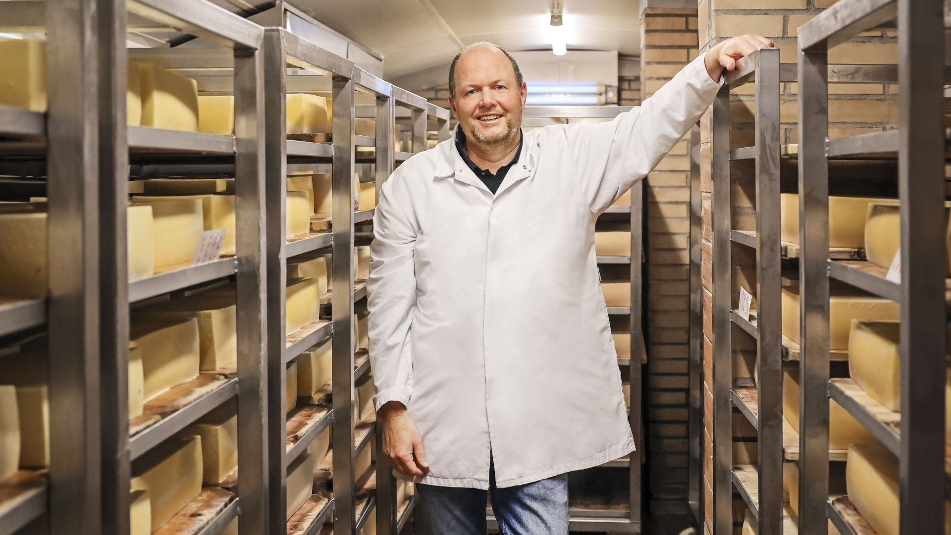Mann steht in der Käse-Reifekammer