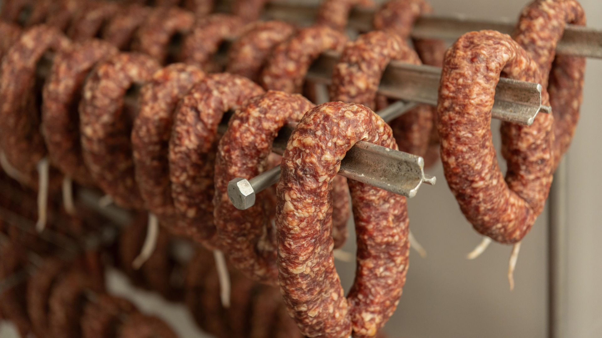 Viele luftgetrocknete Salami-Ringe hängen auf Stangen zum Trocknen