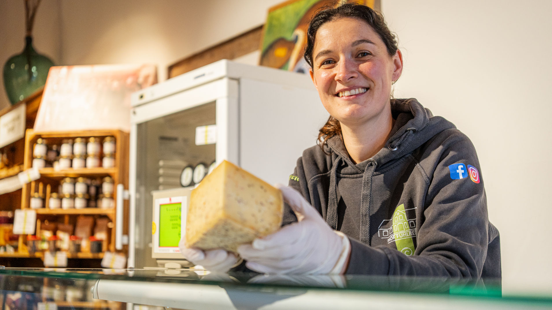 eine Frau präsentiert Käse aus der Käsetheke