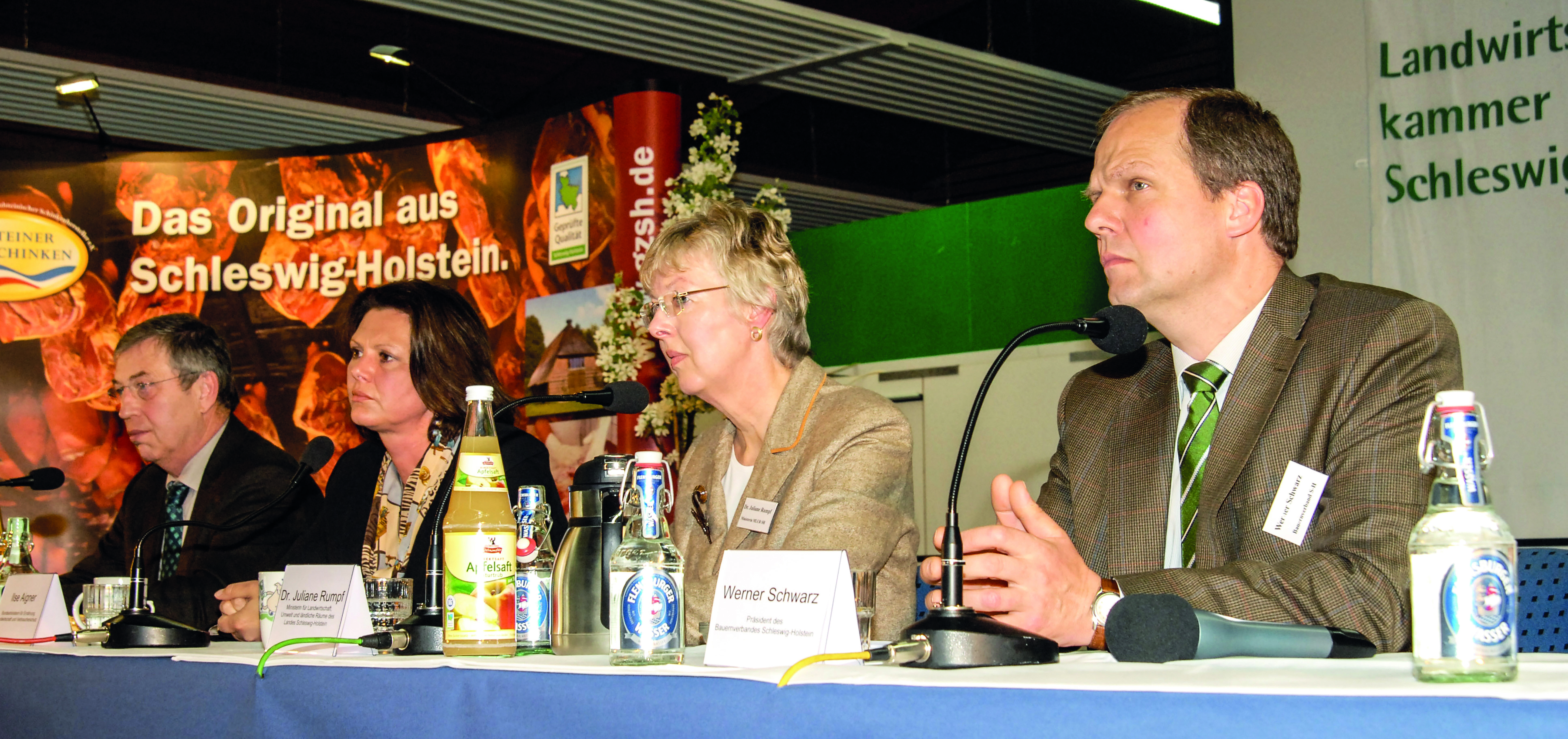 4 Personen sitzen an einem langen Tisch nebeneinander