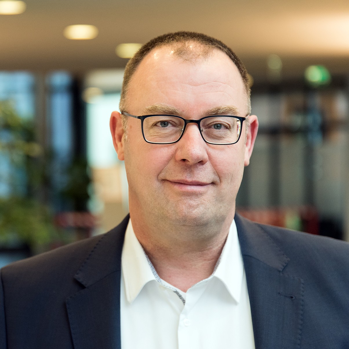 Mann mit Brille im Anzug lächelt in die Kamera